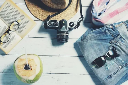 Beach travel essentials on a wooden floor